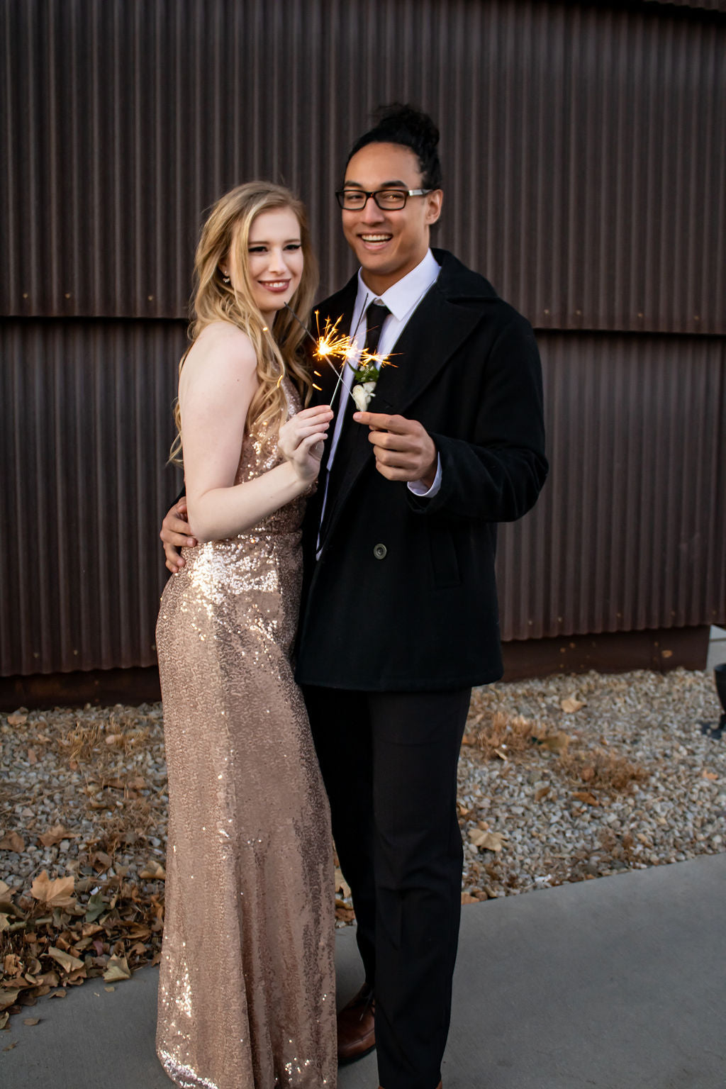 girl in rose gold dress and man in black suit holding 10 inch sparkler celebrating New Year's 