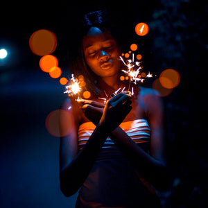 Lady holding two 10 inch sparklers with gold sparks at night