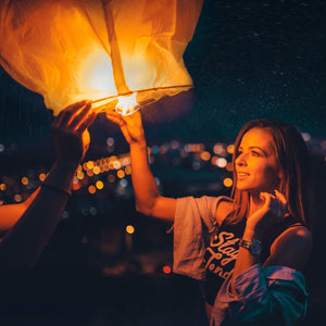 Lady at lantern festival with large paper biodegradable lit with soft gold glow