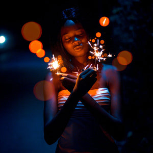 Lady holding two 10 inch sparklers with gold sparks at night 