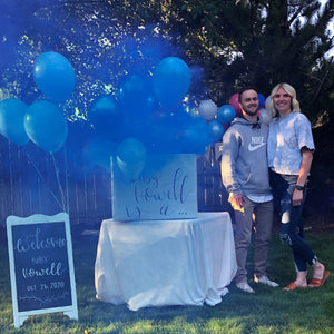 Man and woman with Smoke Bomb Gender Reveal emitting blue smoke from box announcing baby gender reveal