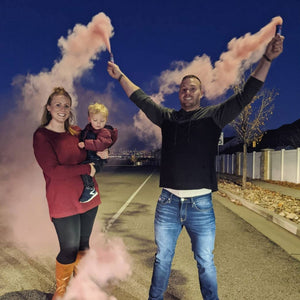 Man holding smoke bomb gender reveal emitting pink clouds of smoke