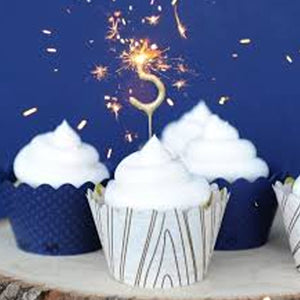 Number sparkler in the shape of 3 on top white frosted cupcake against blue background