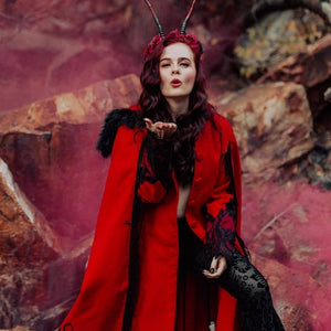Lady dressed in red cape for Halloween with red smoke bomb creating aesthetic background