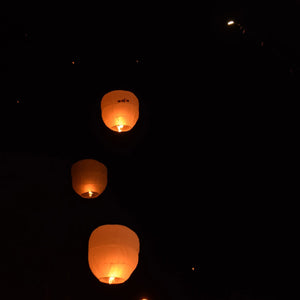 Paper lanterns lit giving off soft gold glow in dark night sky
